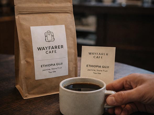 Hand holding a WAYFARER coffee bag during coffee collaboration with brands and cafés